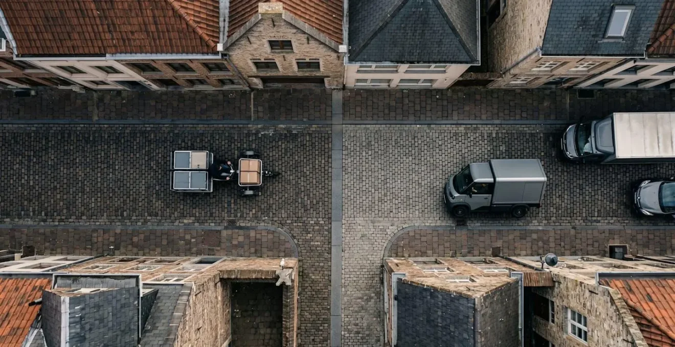 Vue aérienne comparative d'un vélo cargo et d'un utilitaire électrique dans une rue étroite