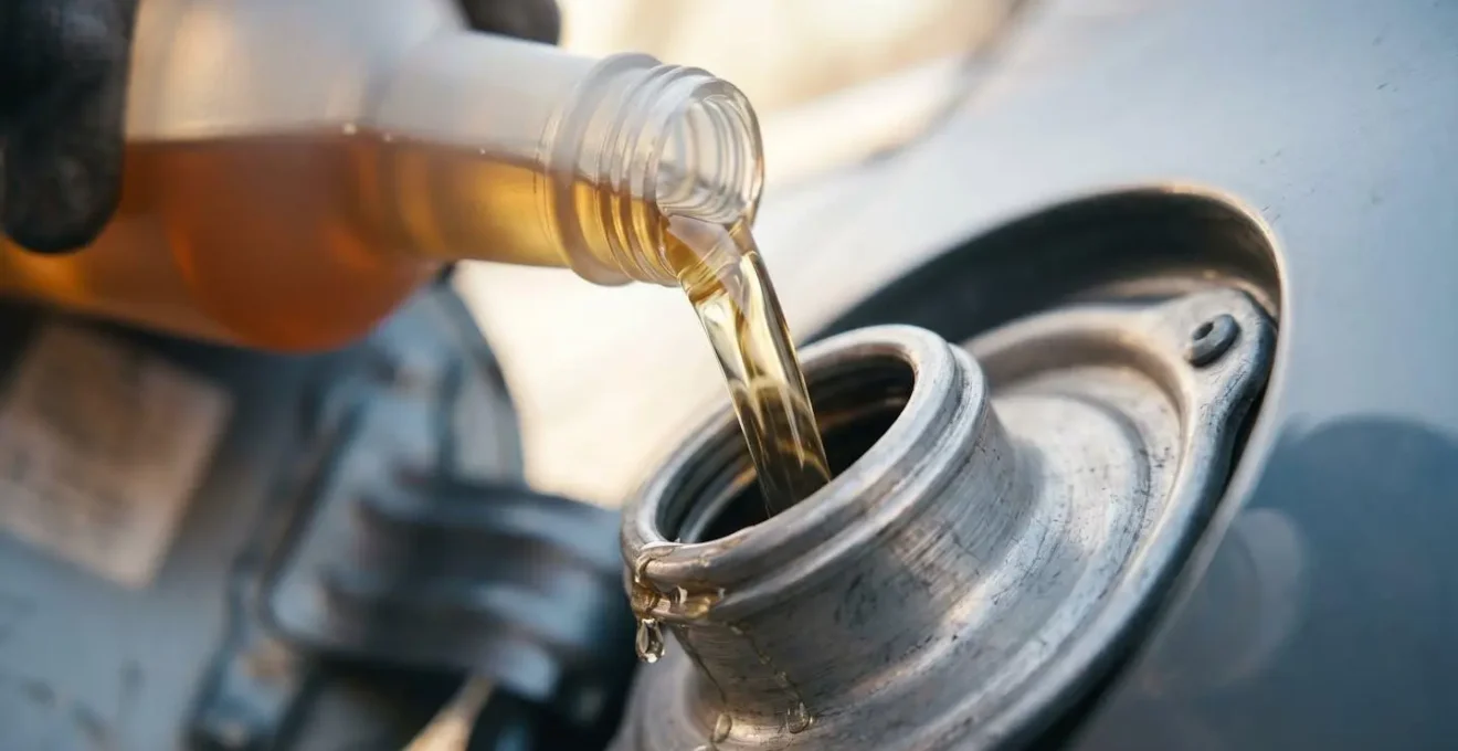 Main versant un additif nettoyant dans le réservoir d'un véhicule diesel