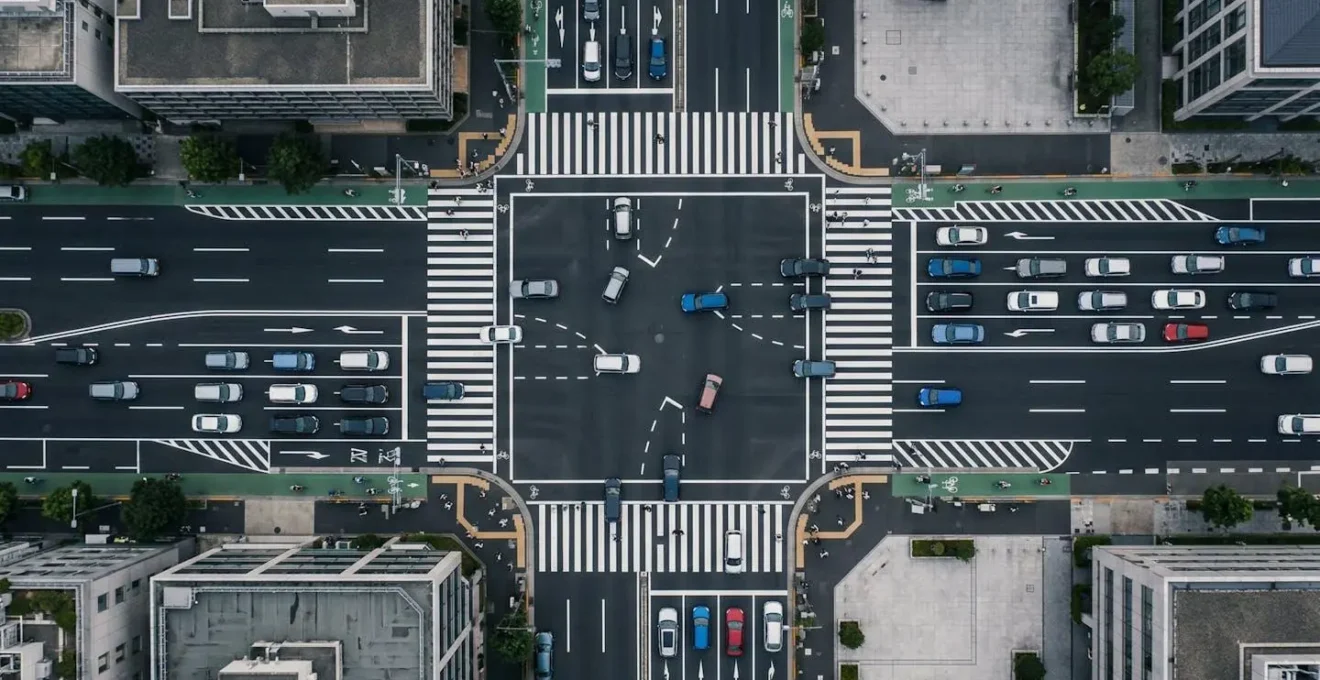 Vue aérienne d'une intersection urbaine montrant la cohabitation entre voitures et nouvelles mobilités